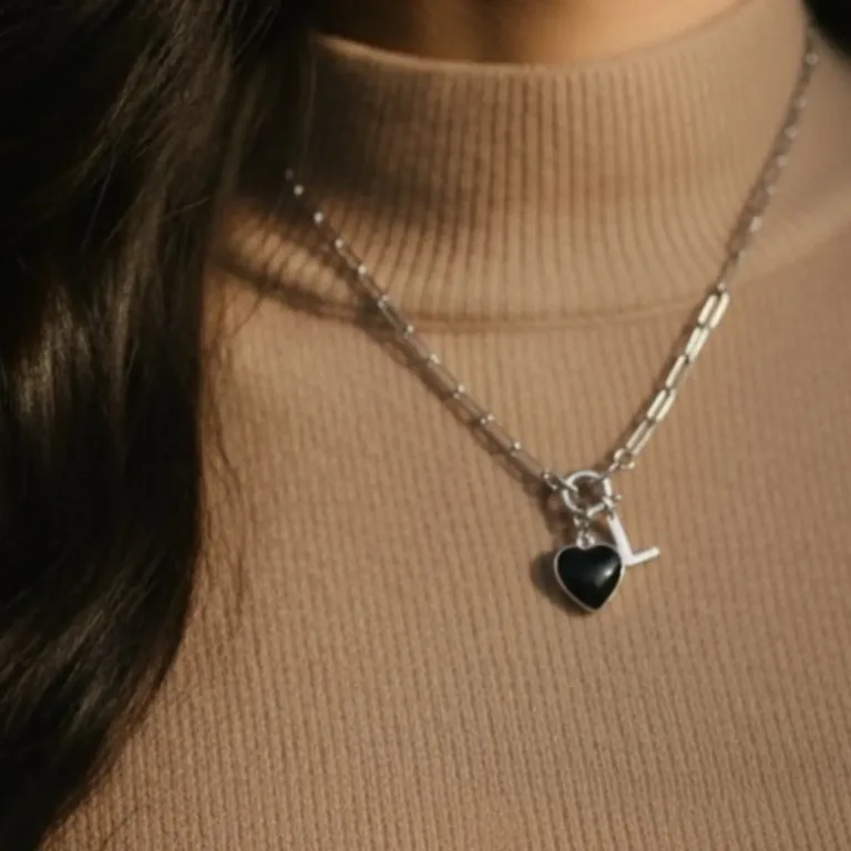 collier connecté en acier inoxydable argenté avec un charm en forme de coeur et résine noire avec une puce NFC et un charm initiale