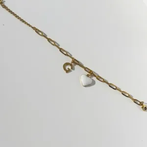 bracelet connecté en acier inoxydable doré avec un charm coeur blanc comportant une puce NFC et un charm initiale