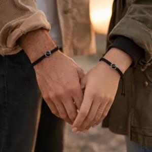 un homme et une femme qui portent des bracelets couple connectés en acier inoxydable argenté et nylon noir