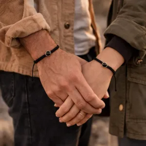 couple qui porte chacun un bracelet connecté noir avec une capsule en acier inoxydable doré et résine noire qui cache une puce NFC